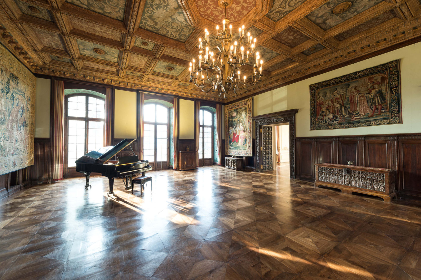 Rittersaal mit Konzertflügel, Kassettendecke und historischen Wandteppichen
